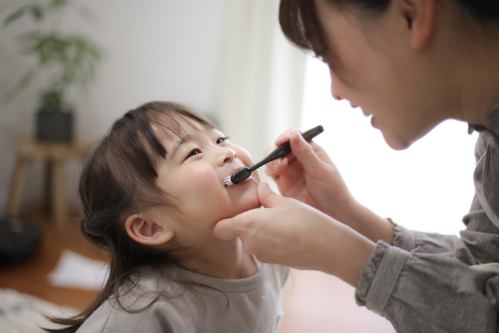子どもの歯を磨いてあげている母親
