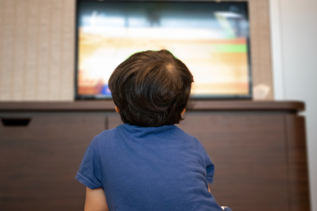 猫背でテレビを見る男の子の後ろ姿